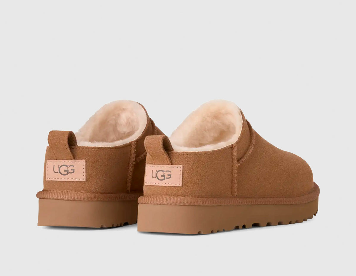 UGG Women's Classic Micro. Rear view of pair of chestnut suede mini boots showing suede heel pull tabs, woven leather heel logo patches, and plush shearling lining. 
