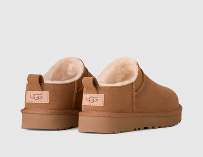 UGG Women's Classic Micro. Rear view of pair of chestnut suede mini boots showing suede heel pull tabs, woven leather heel logo patches, and plush shearling lining. 

