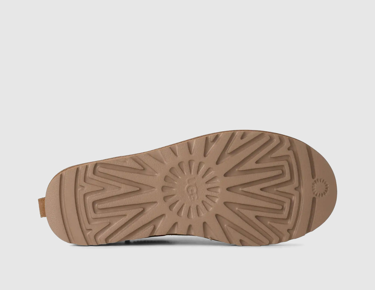 UGG Women's Classic Micro. Bottom view of single chestnut suede mini boot showing matching treaded rubber outsole with sunburst traction pattern and central UGG logo. 