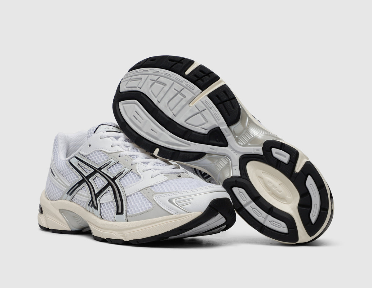 ASICS GEL-1130. Three-quarter view of white running shoes with one shoe turned to showcase the rubber outsole. 
