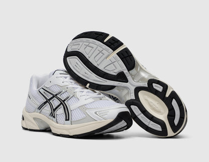 ASICS GEL-1130. Three-quarter view of white running shoes with one shoe turned to showcase the rubber outsole. 