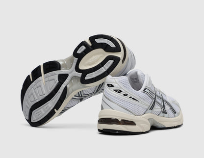 ASICS GEL-1130. Side view of stacked white running shoes showing dark rubber outsole traction pattern and GEL heel cushioning. 