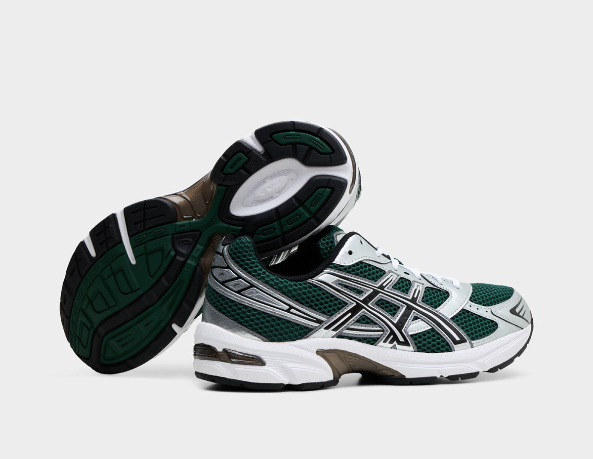 ASICS GEL-1130. Dynamic view of pair of running shoes with one shoe turned on its side to show the dark green and black rubber outsole with midfoot TRUSSTIC shank system. 