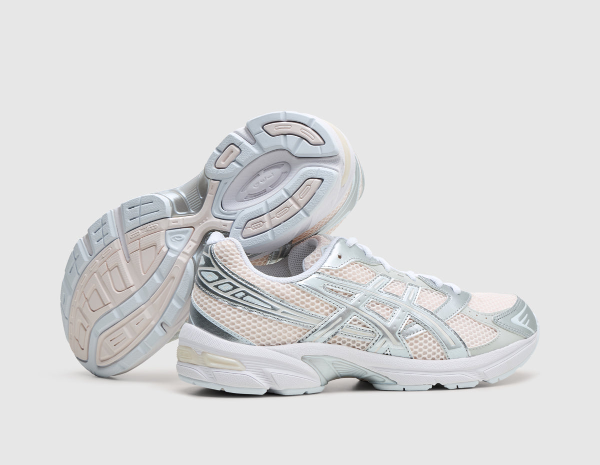 ASICS GEL-1130. Dynamic view of pair of running shoes with one shoe resting on its side to display the light grey and blush rubber outsole with visible midfoot TRUSSTIC shank. 