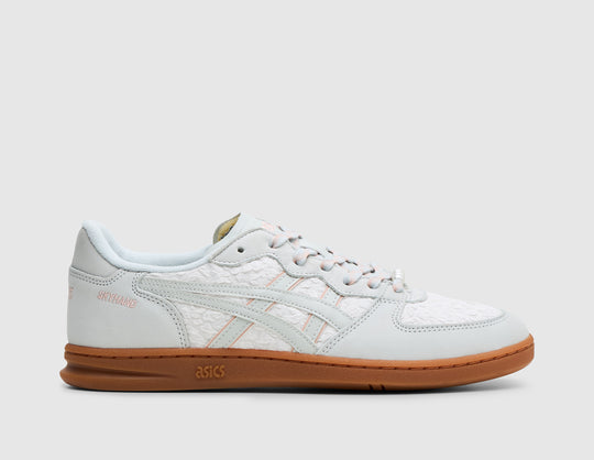 ASICS SKYHAND OG. Side view of glacier grey leather sneakers featuring woven side panels, glacier grey ASICS side stripes with blush pink underlays, blush ASICS branding on heel, and gum rubber outsole. 