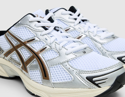 ASICS GEL-1130 Mule. Close-up three-quarter view of white open-back mule sneakers showing white mesh upper, silver overlays, and clay canyon overlays. 