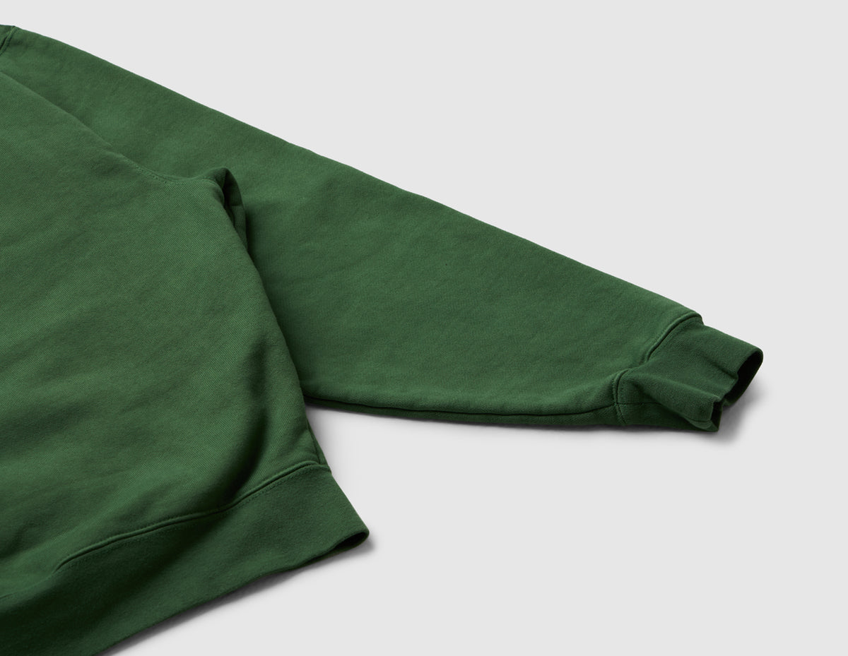 Home Grown Brutal HD Hoodie. Close-up view of dark ivy green pullover hoodie sleeve showing drop-shoulder construction and ribbed cuff detail. 