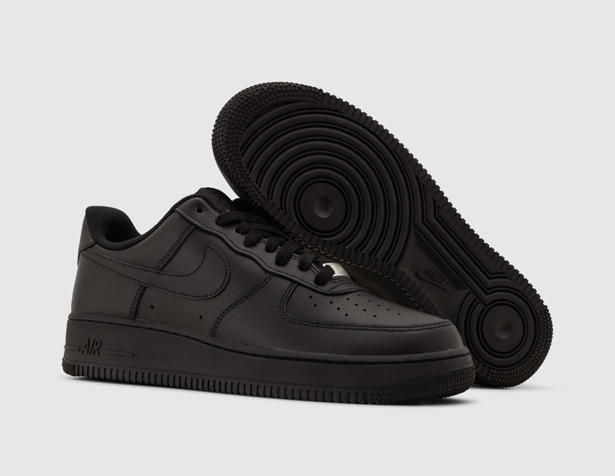 Nike Air Force 1 '07. Three-quarter view of black leather sneakers showing dark rubber traction outsole pattern and silver lace dubrae. 