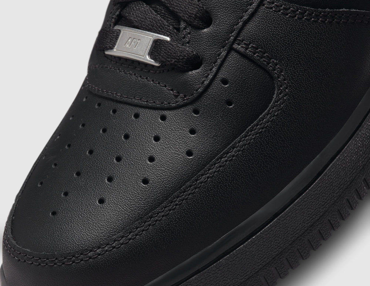 Nike Air Force 1 '07. Close-up of black leather toe box showing perforated ventilation holes and silver metal AF1 lace dubrae. 