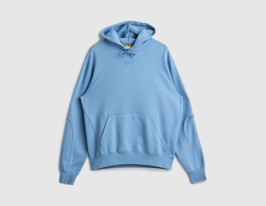 Nike NOCTA Fleece CS Hoodie. Front view of work blue pullover hoodie with kangaroo pocket and center chest Nike Swoosh. 