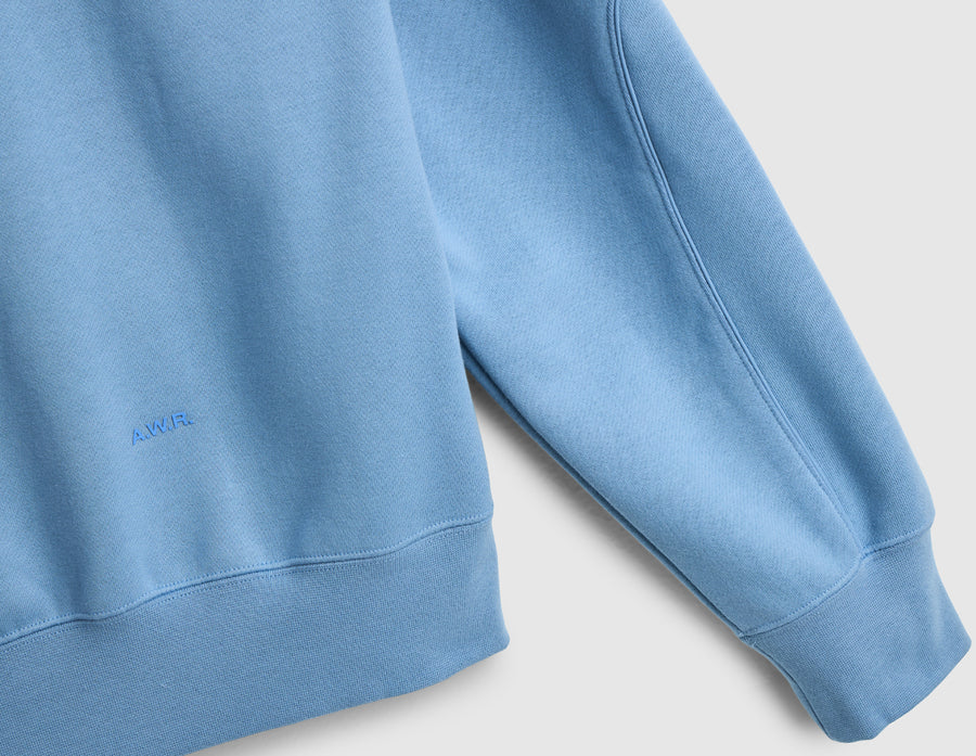 Nike NOCTA Fleece CS Hoodie. Close-up of work blue sleeve panel showing tonal NOCTA branding and ribbed cuff. 