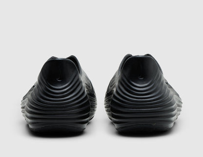 Nike ReactX Rejuven8. Rear view of pair of black molded foam slip-on shoes showing raised heel collars and textured grooves. 