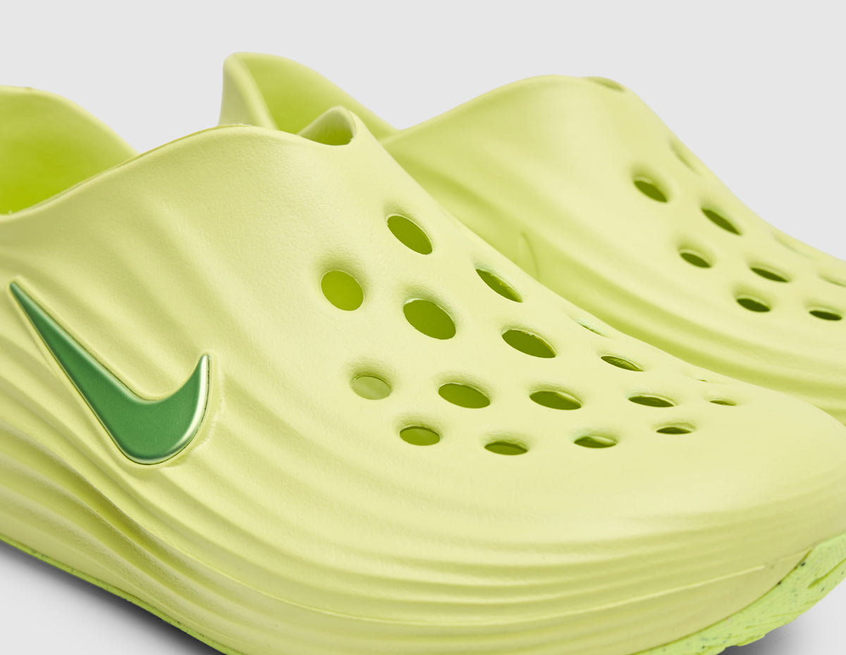 Nike Women's ReactX Rejuven8. Close-up three-quarter view of light lemon twist foam upper showing forefoot circular ventilation cutouts, wave-textured side walls, and green Swoosh logo. 