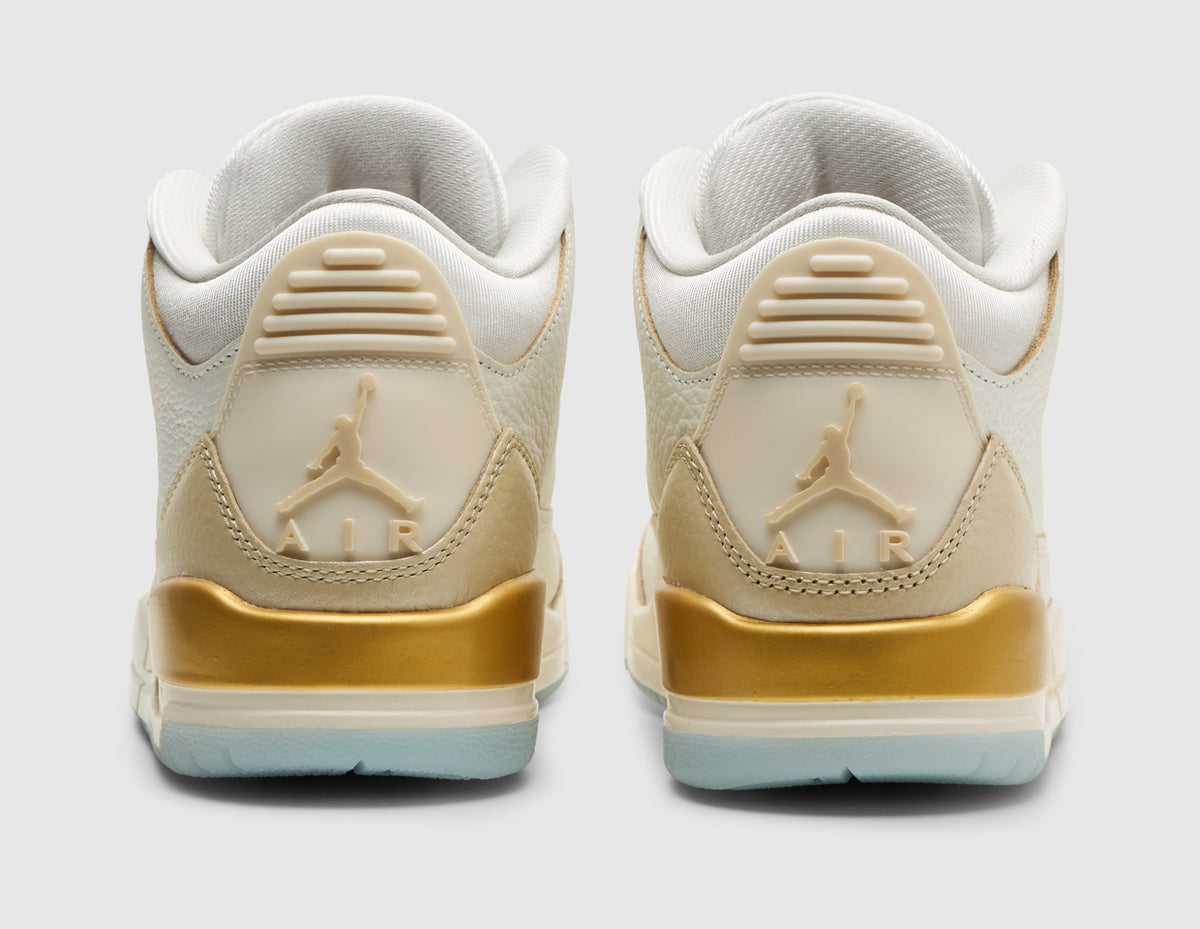 Jordan Women's 3 Retro. Rear view of pair of sail tumbled leather basketball shoes showing embossed pale ivory Jumpman heel tabs, metallic team gold midsole accents, and icy light blue soles. 