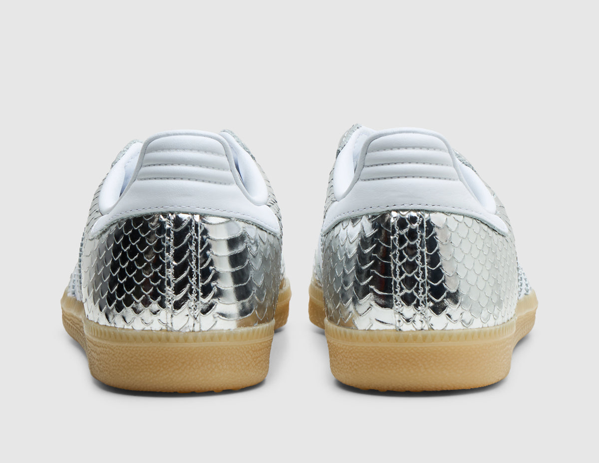 adidas Women's Samba. Rear view of pair of silver metallic snakeskin sneakers showing white leather heel tabs, silver textured heel counters, and gum rubber midsoles. 
