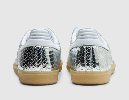 adidas Women's Samba. Rear view of pair of silver metallic snakeskin sneakers showing white leather heel tabs, silver textured heel counters, and gum rubber midsoles. 