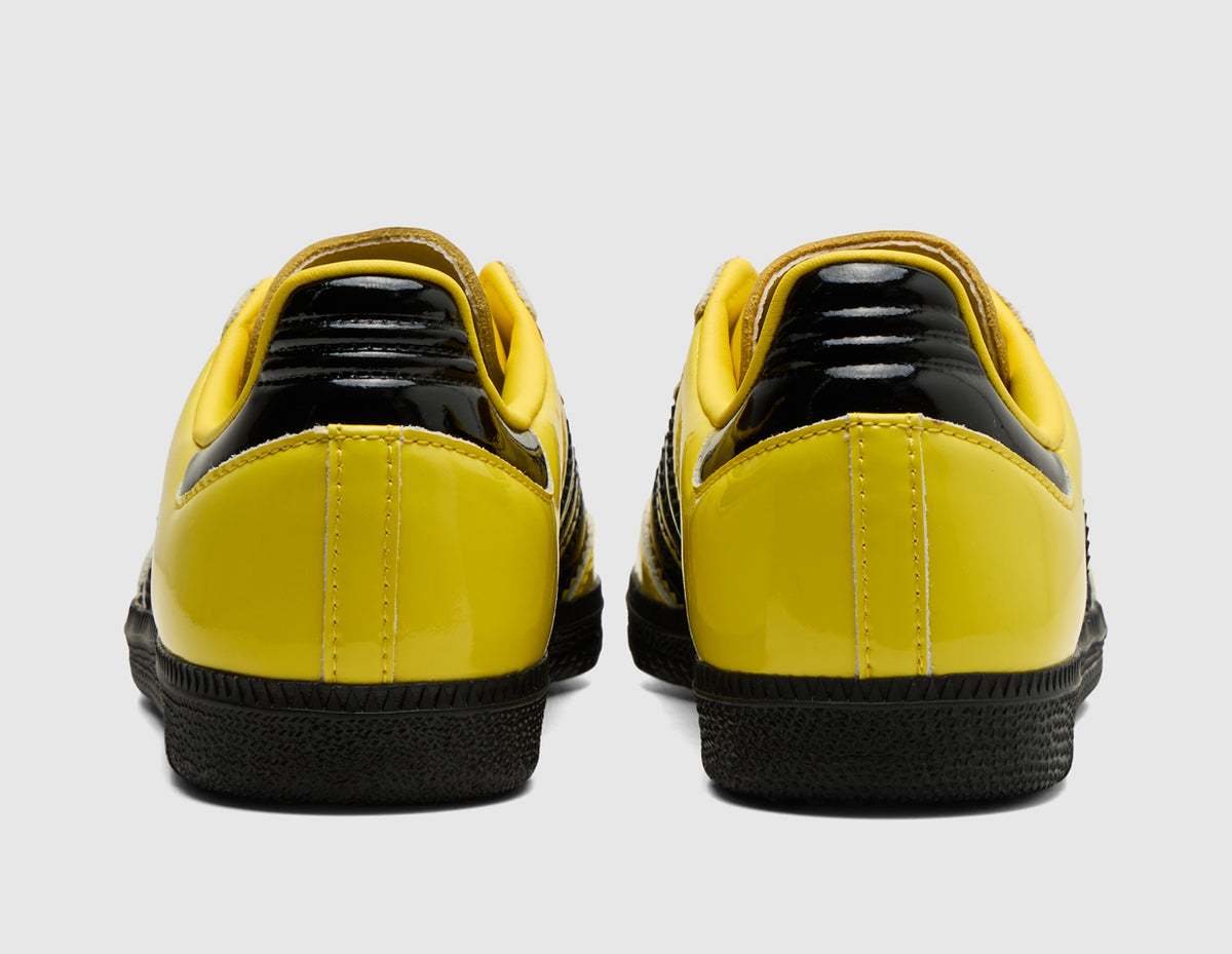 adidas Originals Samba OG. Rear view of pair of yellow leather sneakers showing black heel tabs and low-profile black rubber soles. 