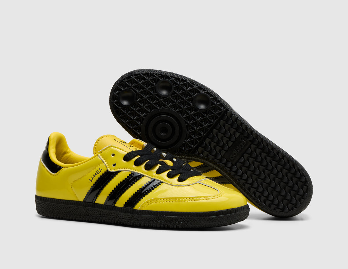adidas Originals Samba OG. Three-quarter view of yellow leather sneakers with one shoe turned to showcase the black rubber outsole. 