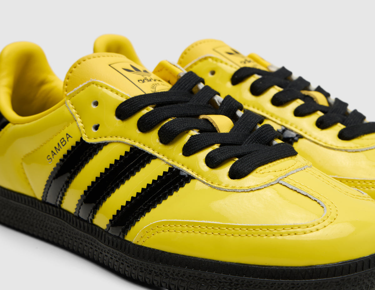adidas Originals Samba OG. Close-up three-quarter view of yellow leather upper, black laces, yellow Trefoil tongue patch, and yellow T-toe overlay. 