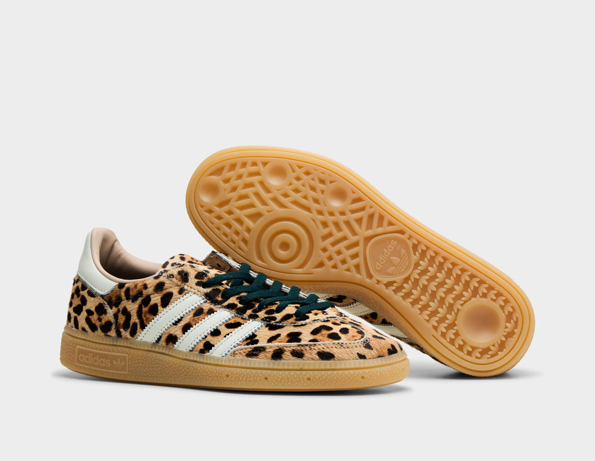 adidas Women's Handball Spezial. Three-quarter view of leopard print sneakers with one shoe turned to showcase the gum rubber outsole.
