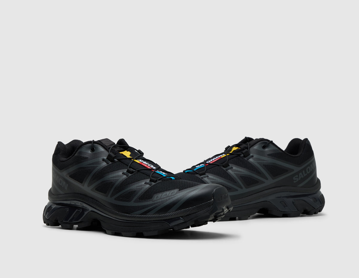 Salomon XT-6. Three-quarter view of pair of triple black trail running shoes showing Quicklace toggle system and signature colorful tongue tag. 