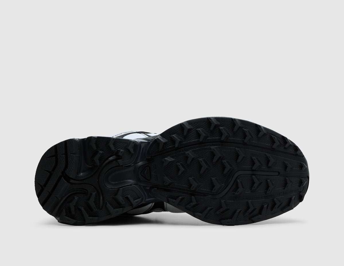 Salomon XT-Whisper. Bottom view of single black and white trail running shoe showing black Contagrip rubber lugged traction outsole pattern. 