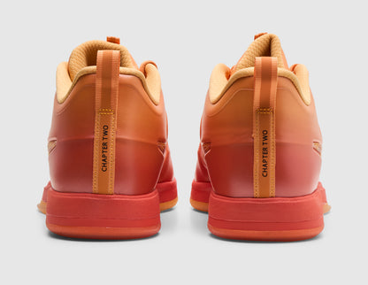 Nike Book 2 "The Phoenix". Rear view of pair of sundial orange basketball shoes showing orange-to-red gradient heel panels, heel pull tabs that read CHAPTER TWO, and solid red midsole base. 
