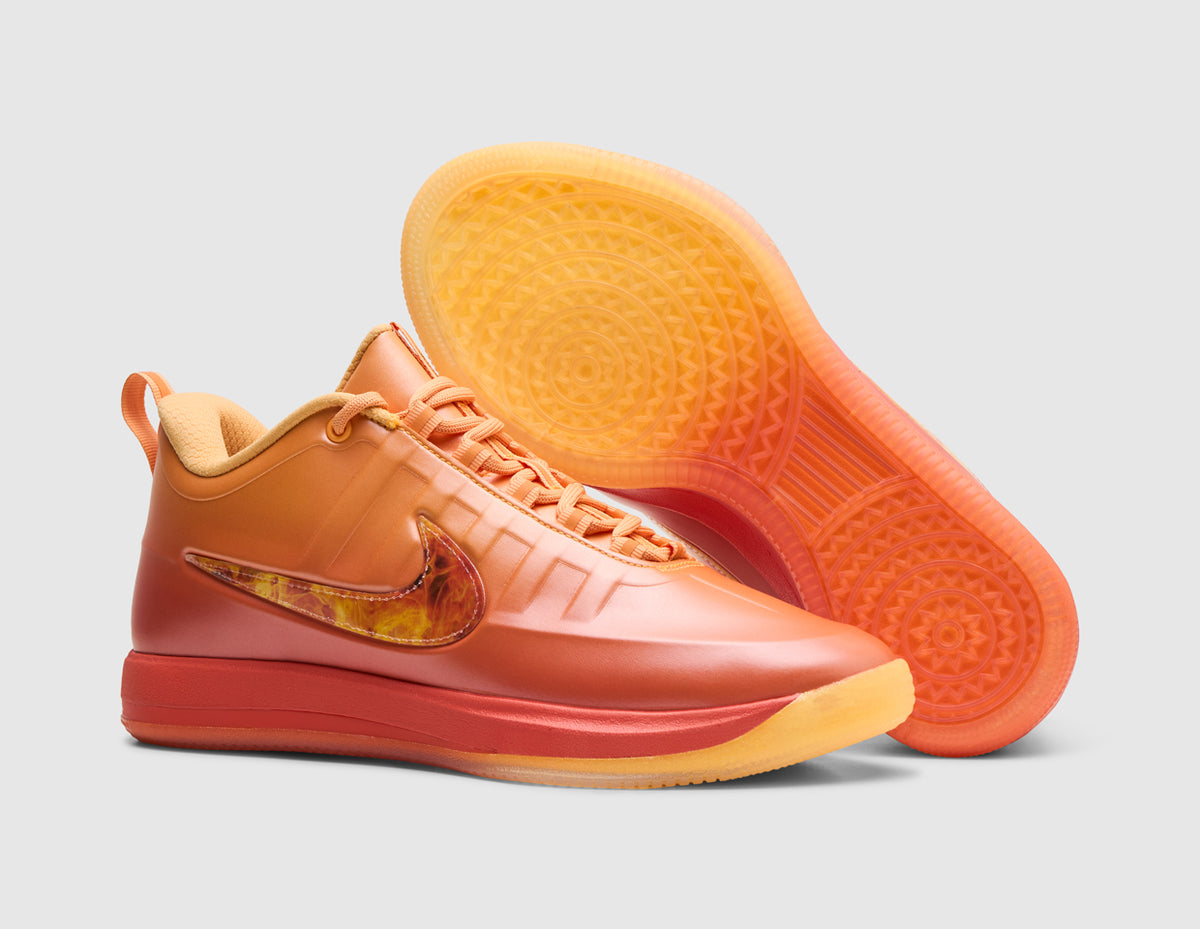 Nike Book 2 "The Phoenix". Three-quarter view of sundial orange basketball shoes with one shoe propped to display the translucent gum rubber outsole. 