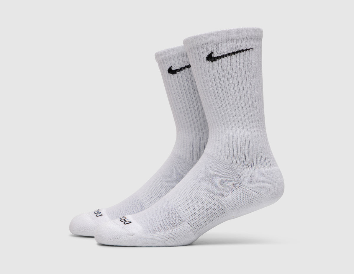 Nike Everyday Plus Cushioned Socks (3-Pack). Side view of white crew socks showing black embroidered Nike Swoosh logos and cushioned soles. 