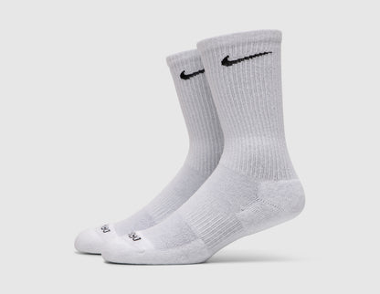Nike Everyday Plus Cushioned Socks (3-Pack). Side view of white crew socks showing black embroidered Nike Swoosh logos and cushioned soles. 