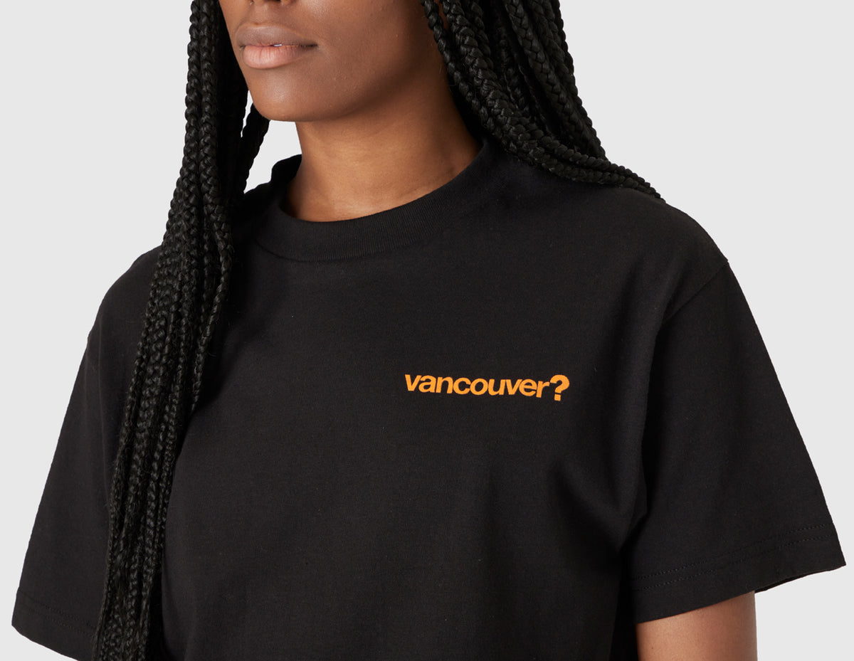 size? Vancouver Logo T-Shirt. Close-up model view of female model highlighting the orange printed "vancouver?" logo on the left chest. 