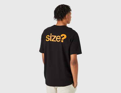 size? Vancouver Logo T-Shirt. Rear model view showing male model in black t-shirt featuring large orange printed "size?" graphic across the back shoulders. 