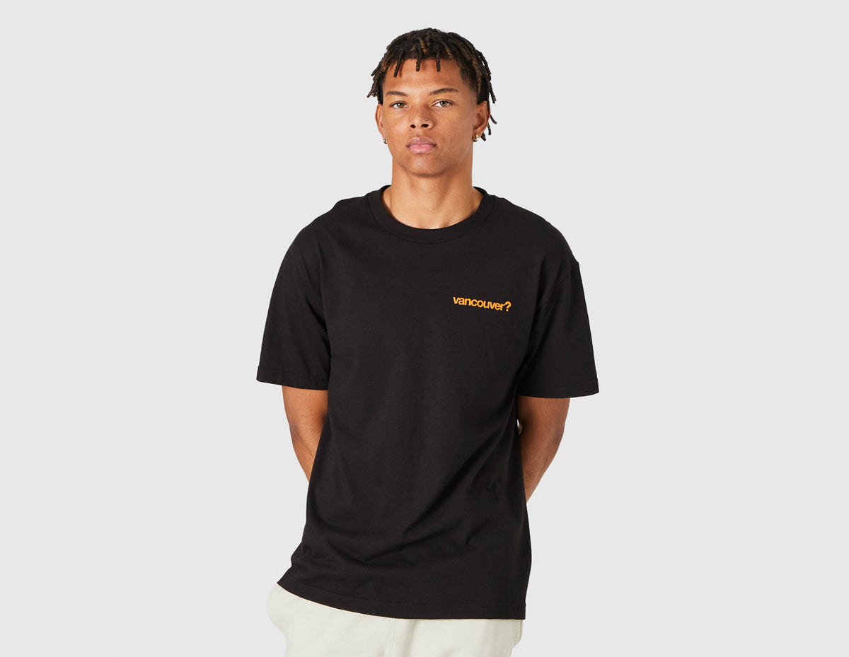 size? Vancouver Logo T-Shirt. Front model view of black shortsleeve t-shirt featuring a crewneck collar and orange printed "vancouver?" text logo on the left chest. 